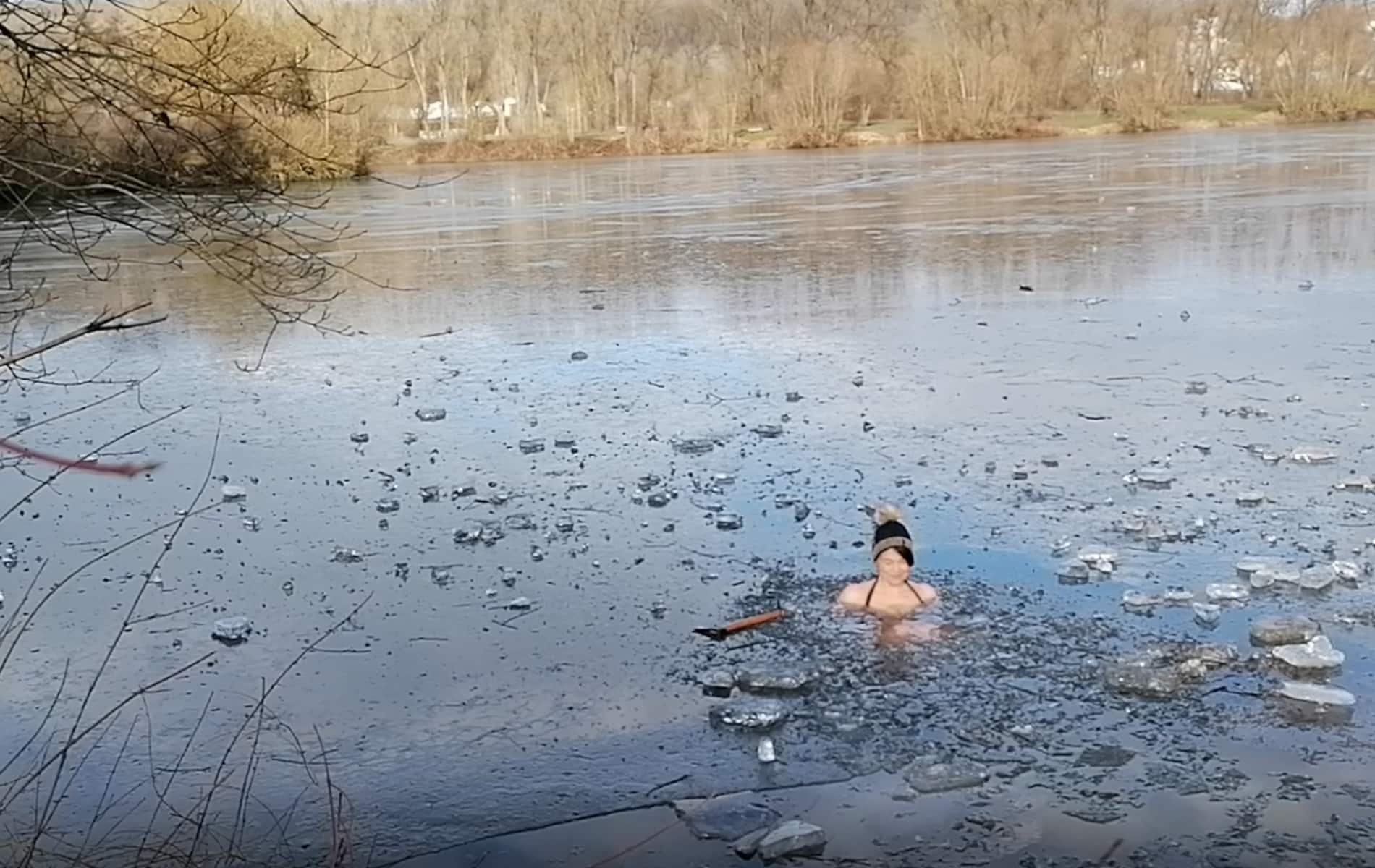 Frau badet zwischen Eisplatten nach Wim Hof im Wasser