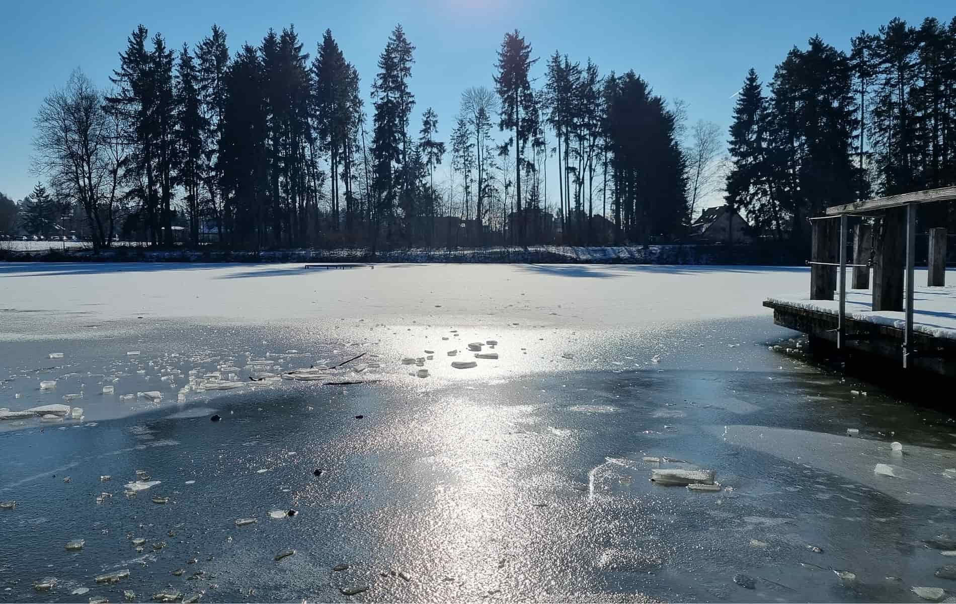 Blick auf zugefrorenen See mit Bäumen im Hintergrund
