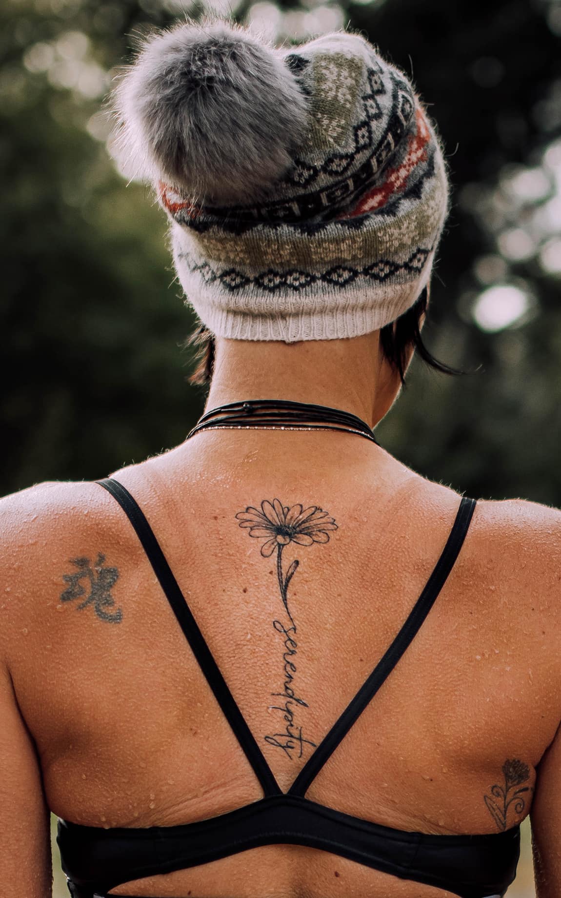 Rücken einer Frau mit Wintermütze im Bikini mit dezentem Tattoo