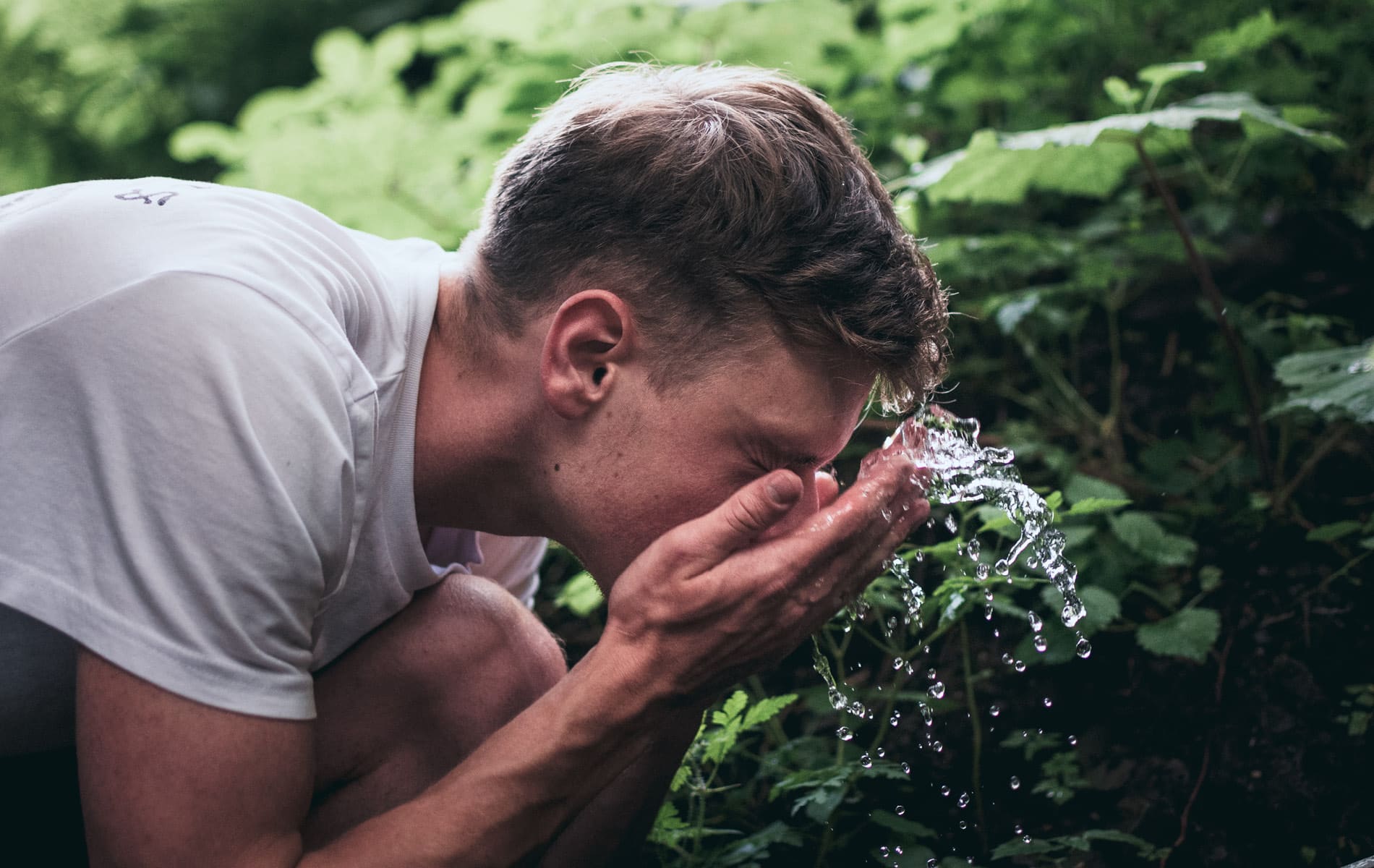 Mann wäscht sein Gesicht mit Wasser