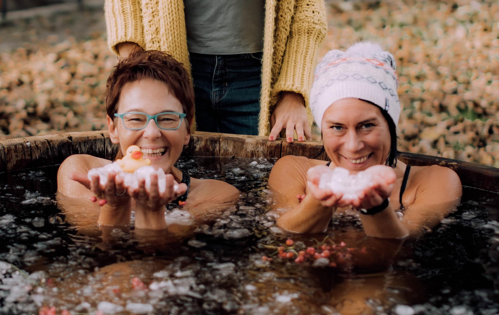 Zwei Frauen sitzen lachend im Eisbadezuber