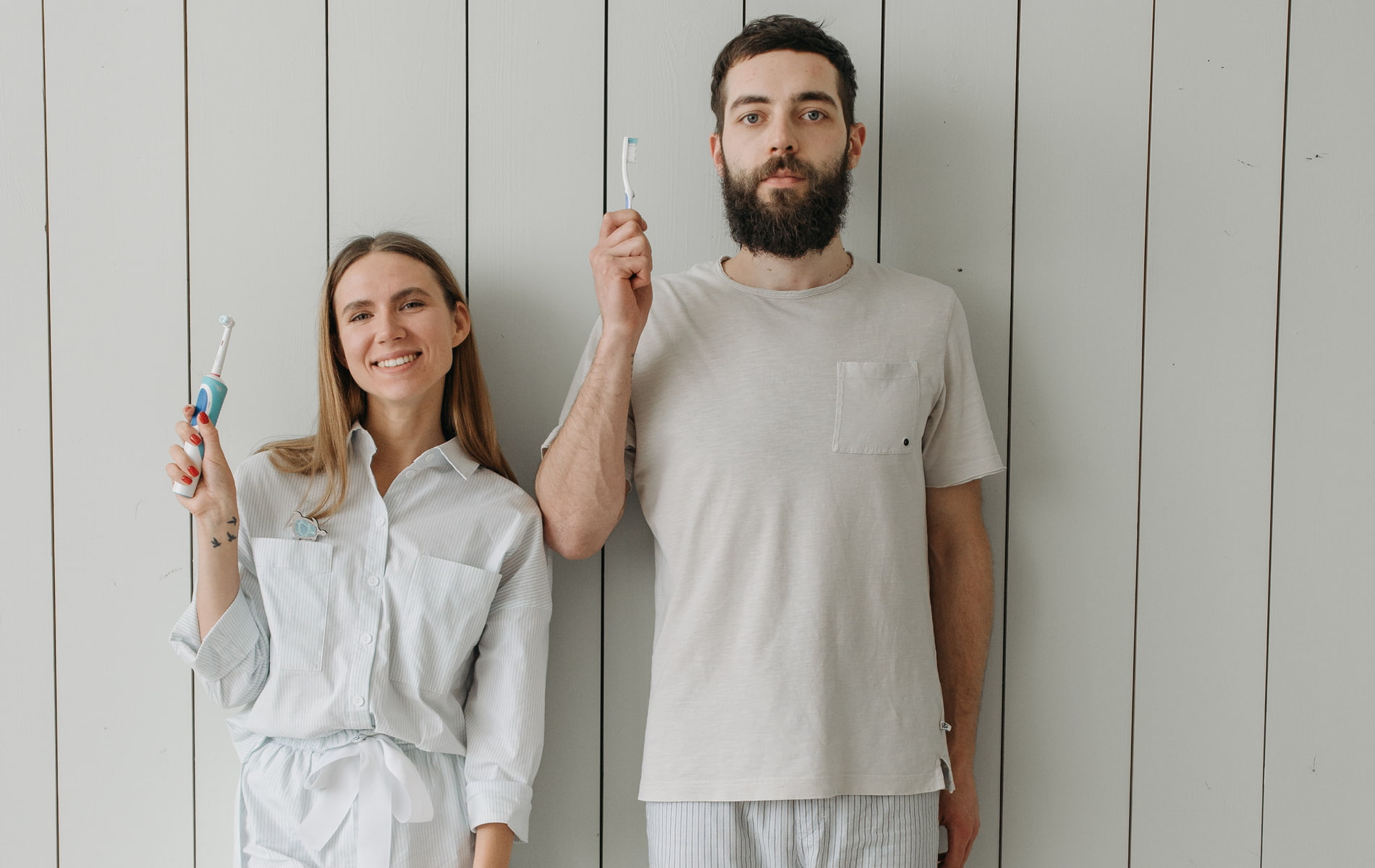 Mann und Frau im Schlafanzug und Zahnbürste in der Hand