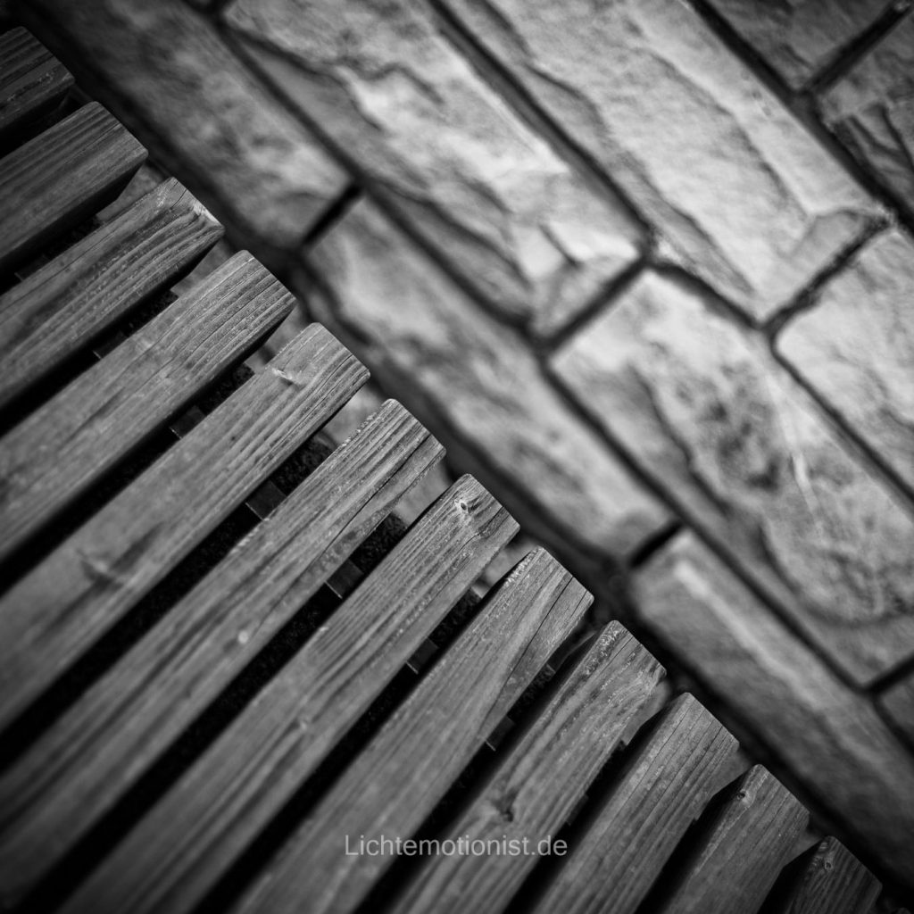 Holzstreben mit Steinmauer im Hintergrund in schwarz-weiß