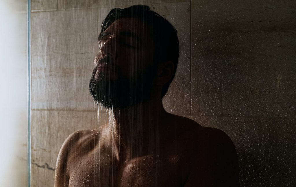 Mann mit geschlossenen Augen unter Dusche