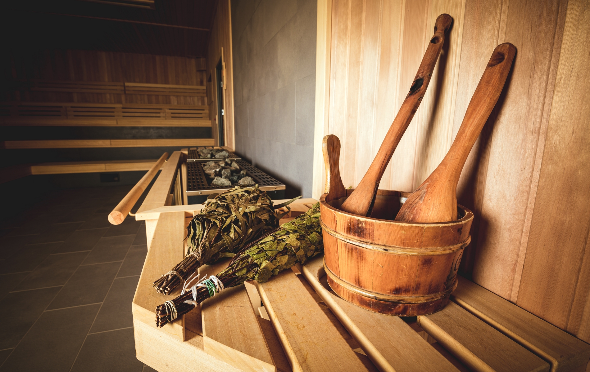 Eine Saunabank mit Sauna Holzfass, Schöpfkelle und Zweigen