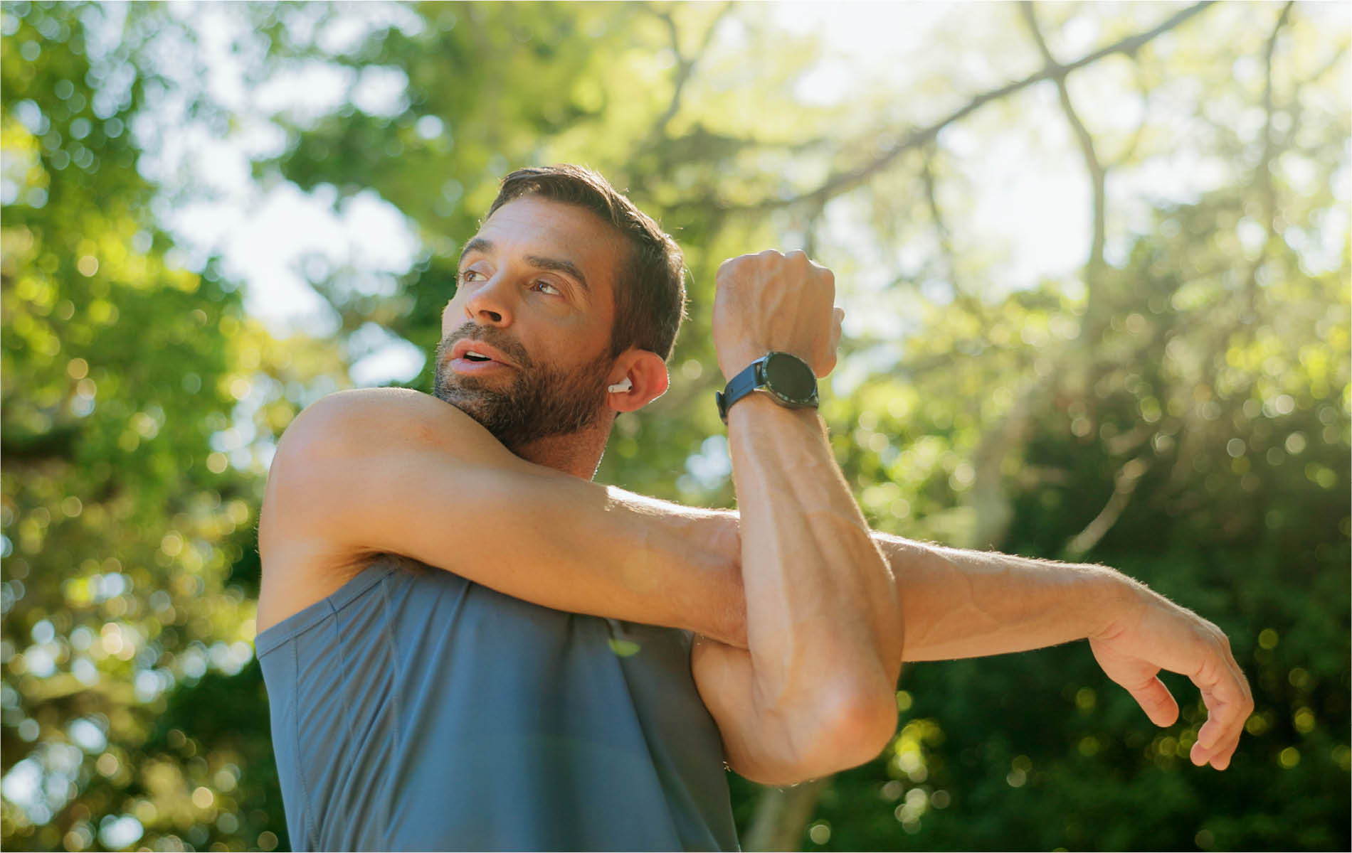 Mann der Im Wald steht und Dehnübungen für die Arme macht